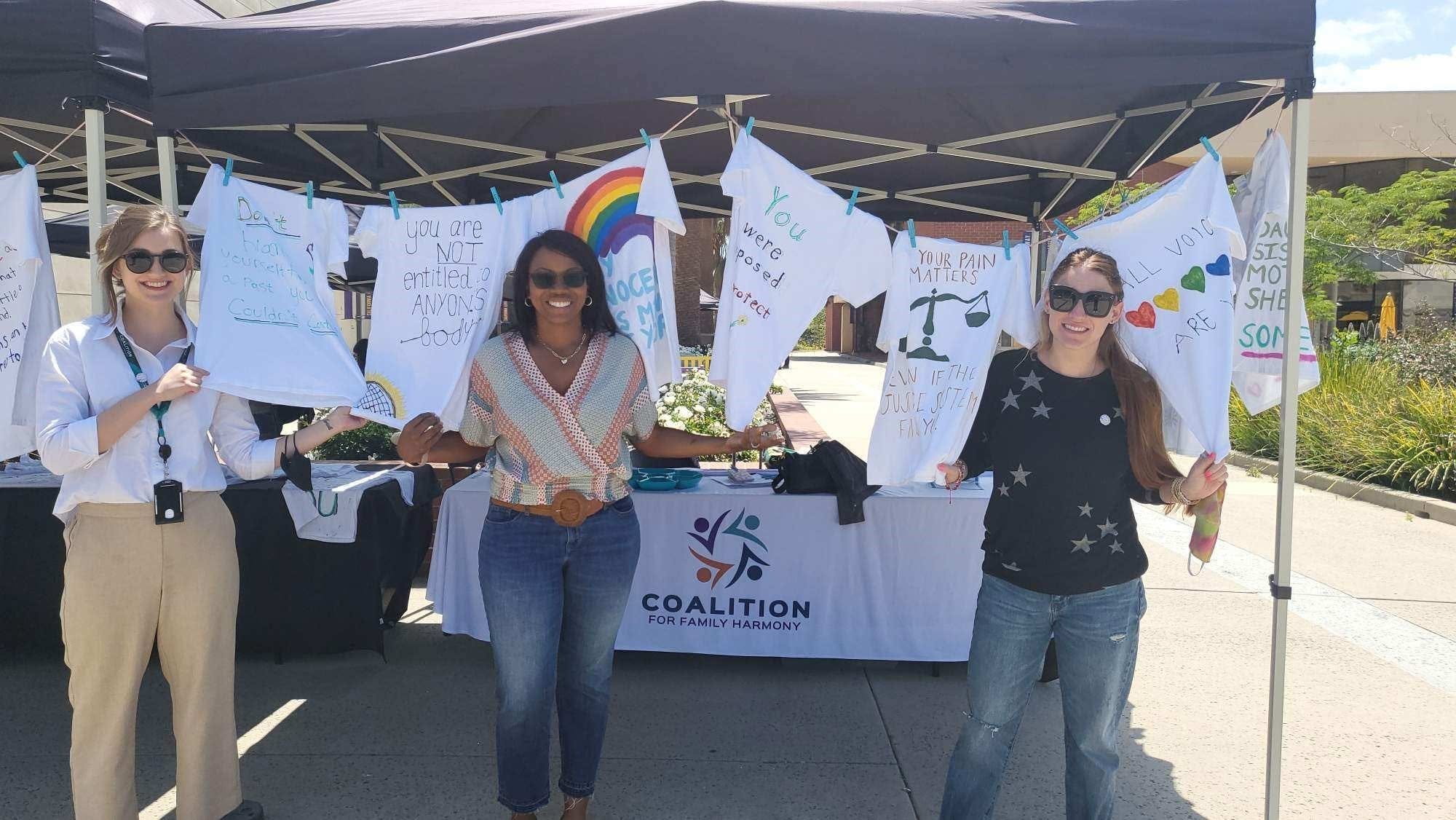 Three Coalition advocates holding Clothesline Project shirts